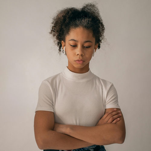 A young girl standing with a tired expression, slumped over his books, illustrating low energy and lack of motivation.