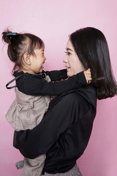 A young girl clinging to her mother, illustrating a common behavior in toddlers seeking comfort.