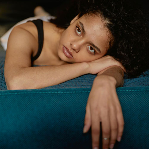 A teenage girl lying on her bed with a sad expression, illustrating depression in teenagers.